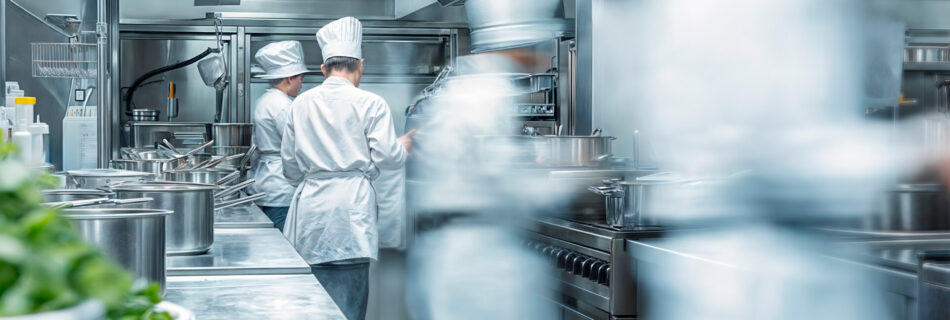 Modern commercial kitchen with chefs working in the back ground cooking food